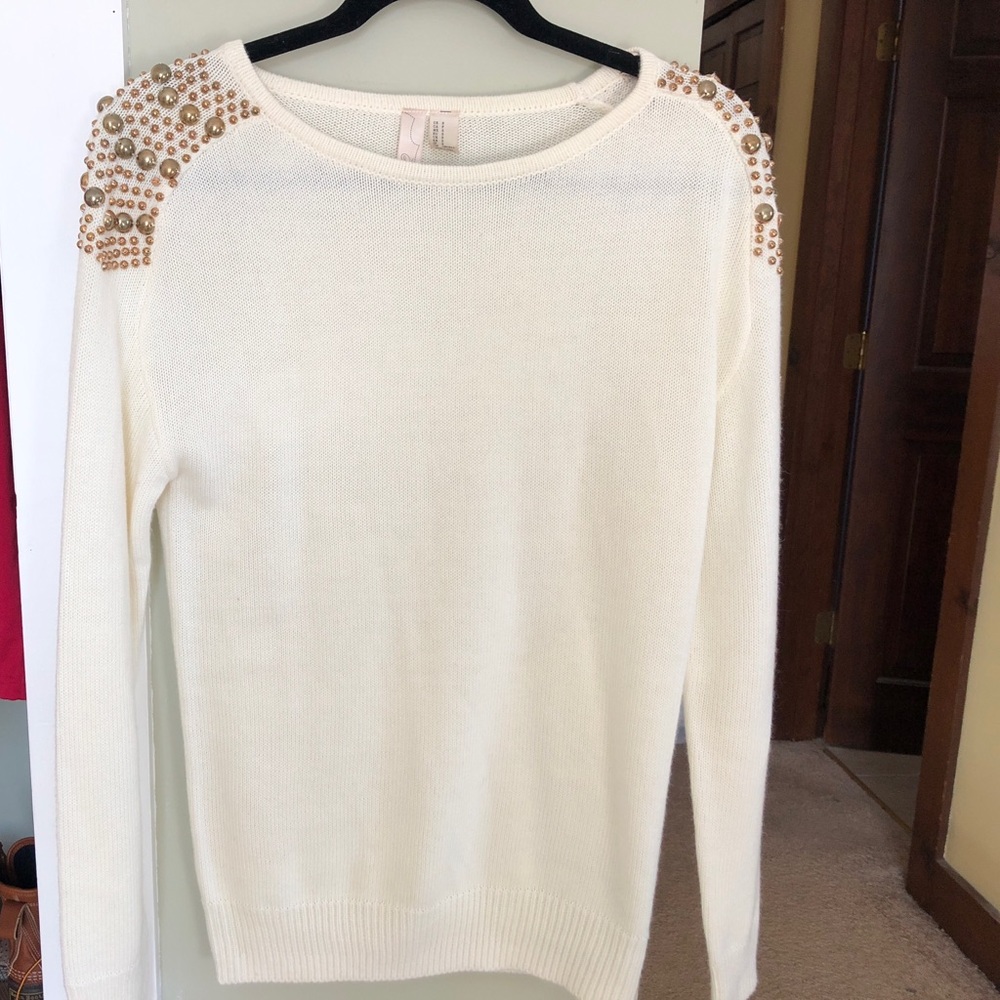 Cream colored sweater with gold embellishments.